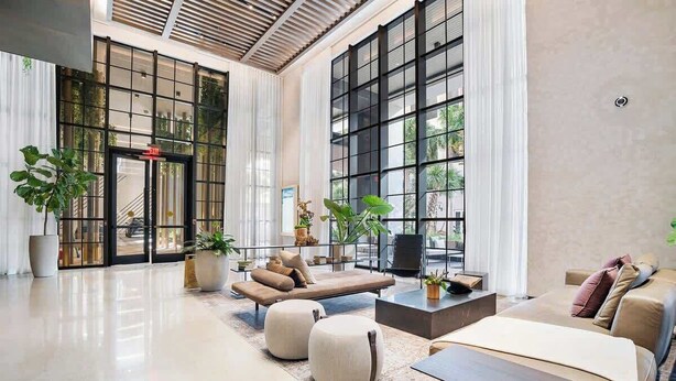 Eine großzügige Lobby mit modernem Design, ausgestattet mit einer geräumigen Sitzecke, Sofas, Poufs, einem Couchtisch und Pflanzen in Töpfen.