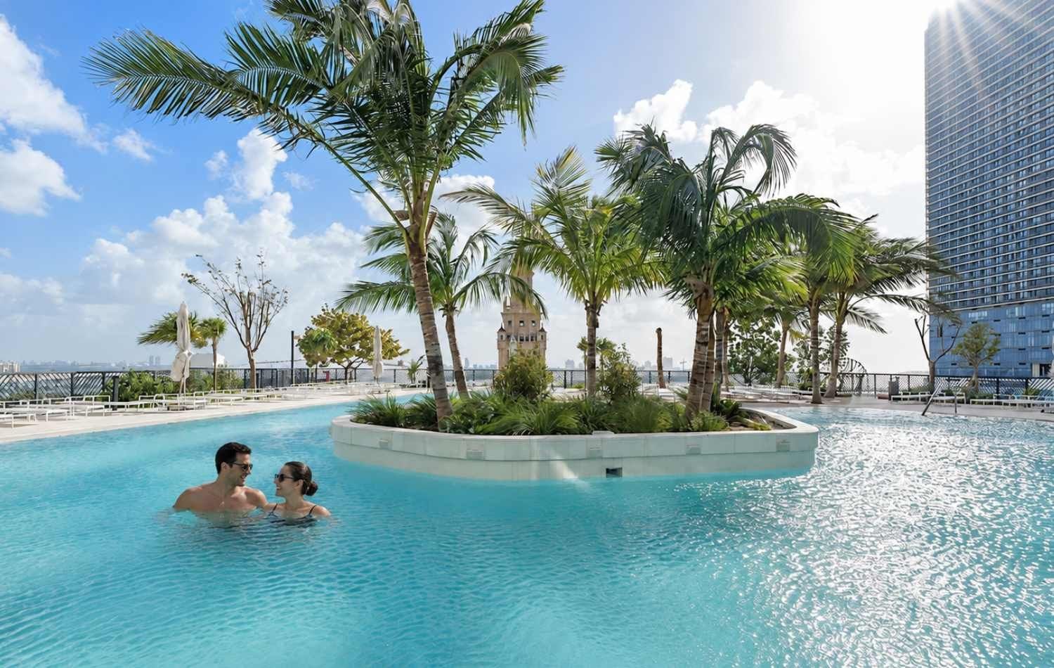 En swimmingpool med palmer och utsikt över en stads silhuett.