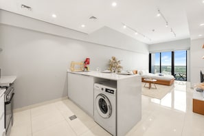 Eine moderne Küche mit eingebauter Waschmaschine, einem Essbereich mit Sofa und einem großen Fenster mit Blick.