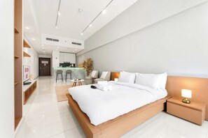 Ein modernes Hotelzimmer mit einem großen Bett, einem Nachttisch mit Lampe, einem kleinen Schreibtisch und einer Sitzecke mit Stühlen und einem Tisch.
