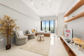 Ein modernes Wohnzimmer mit Sofa, Couchtisch, Blumentopf und Fernseher mit dem Schild 'BOOK ME'.