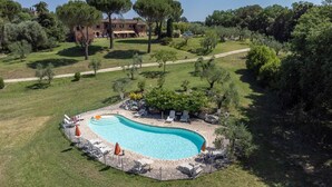 A swimming pool with lounge chairs and umbrellas, surrounded by a stone deck. - Agriturismo Siena With Pool (Siena)