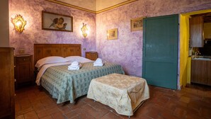 A bedroom with a bed, a bedside table, a nightstand, a green door, and a small table with a tablecloth. - Agriturismo Siena With Pool (Siena)