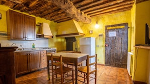 A kitchen with wooden cabinets, a tiled floor, and a rustic ceiling. - Agriturismo Siena With Pool (Siena)