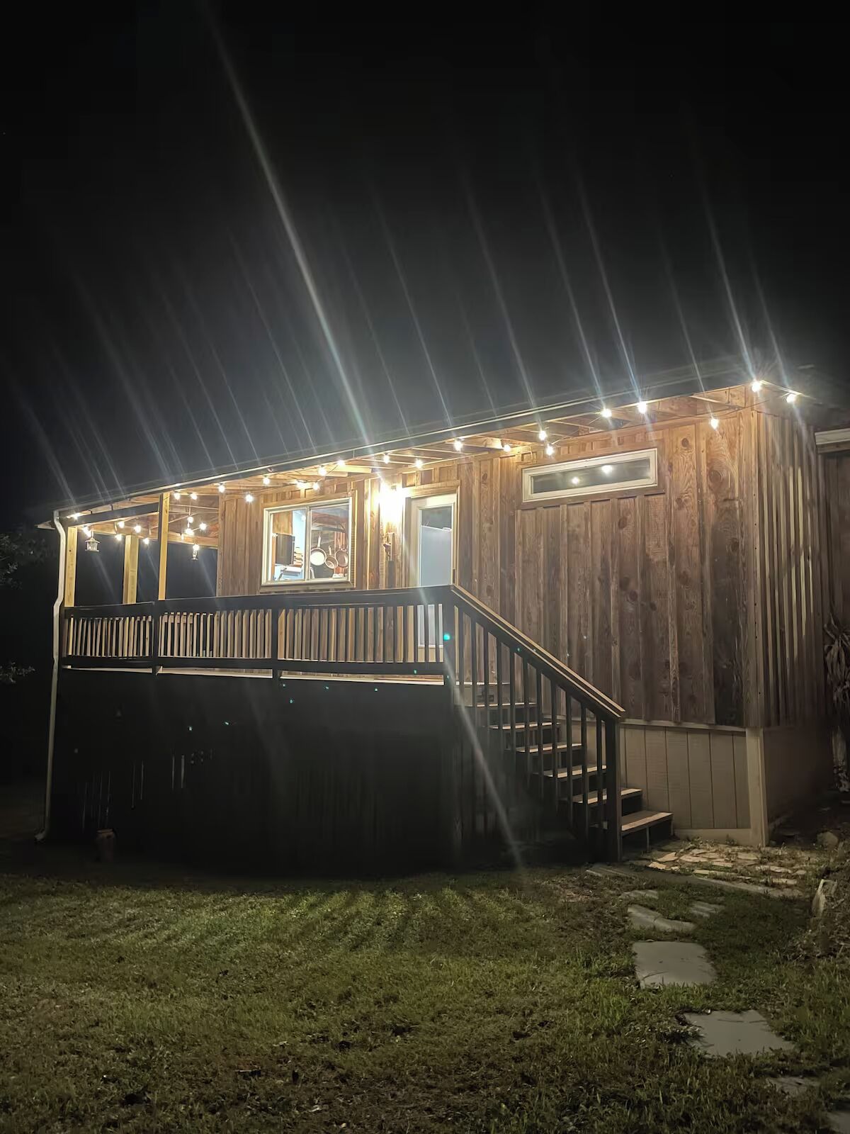 Eine Holzhütte mit einer Terrasse, Treppen und Lichterketten.