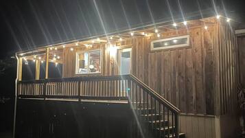 Eine Holzhütte mit einer Terrasse, Treppen und Lichterketten.