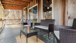Un espace extérieur aménagé avec des meubles en osier, une table en verre et une vue sur le paysage.