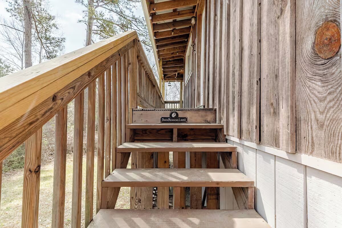 Una escalera de madera lleva a una terraza con un letrero que dice 'Perros sueltos'.