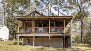 Une cabane en bois à deux étages, dotée d’un balcon, d’un garage et d’un petit abri attenant.