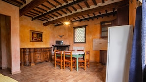 Une cuisine rustique avec une table à manger, des chaises, un réfrigérateur et une fenêtre donnant sur un beau paysage.