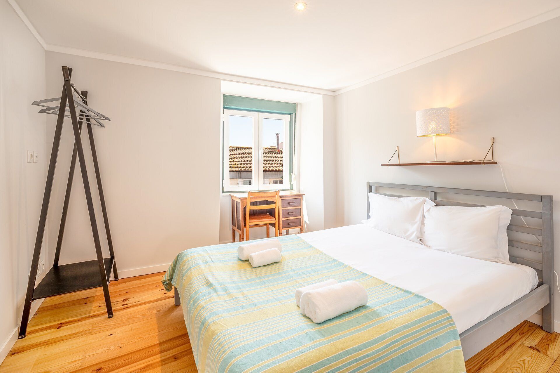 A hotel room with a bed, a desk, and a window.