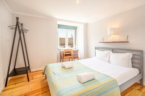 A hotel room with a bed, a desk, and a window.