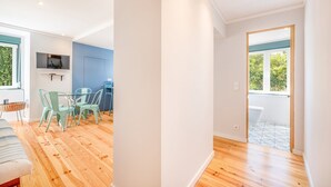 A modern interior with a dining area, a TV mounted on the wall, and a view of the outdoors through a window.
