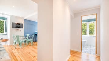 A modern interior with a dining area, a TV mounted on the wall, and a view of the outdoors through a window.
