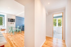 A modern interior with a dining area, a TV mounted on the wall, and a view of the outdoors through a window.
