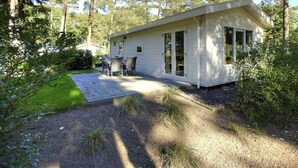 A single-story cabin with a patio, surrounded by trees. - Unique Nouveau 4 (Otterlo)