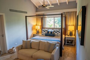 Ein Schlafzimmer mit einem Himmelbett, einer Couch, Nachttischen und einem Deckenventilator.