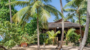 Une plage avec des chaises longues blanches et des palmiers.