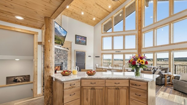 A spacious kitchen with wooden cabinets, a granite countertop, and large windows offering a view of the outdoors. - Eagle Eye Retreat (Island Park)