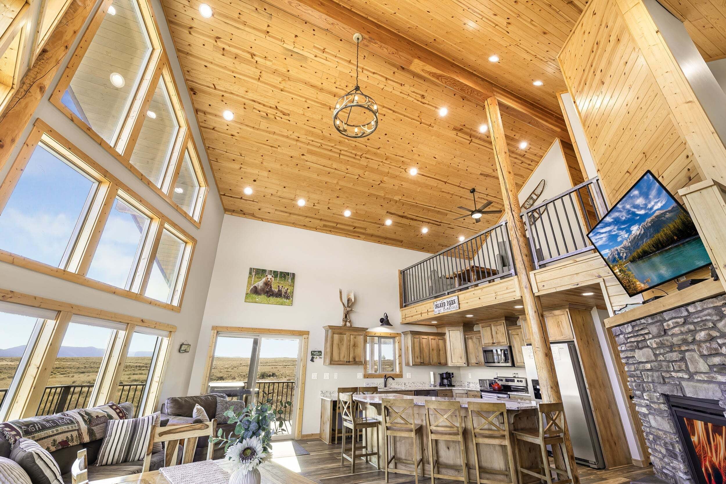 A spacious interior with a high ceiling, large windows, a kitchen, a dining area, and a fireplace.