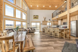 A spacious kitchen with wooden cabinets, a dining area with a large table, and a view of the mountains through large windows.
