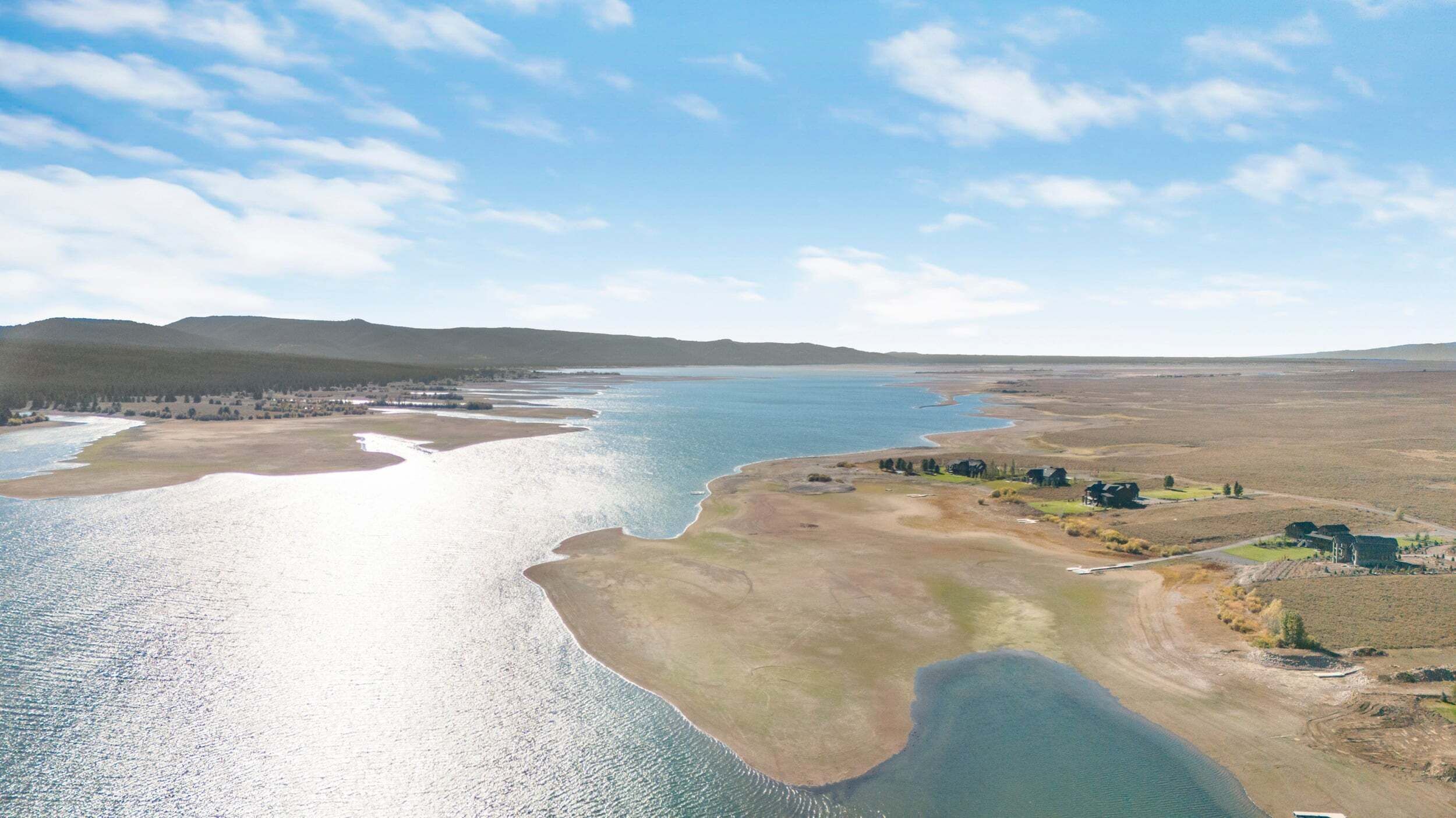 Een kustlandschap met een rivier, een kleine nederzetting en heuvels in de verte.