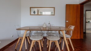 Un coin repas avec une table en bois et des chaises en plastique transparent, une porte en bois et un miroir au mur.