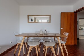 Ein Essbereich mit einem Holztisch, klaren Plastikstühlen, einer Holztür und einem Spiegel an der Wand.