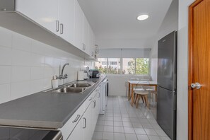 Eine moderne Küche mit weißen Schränken, Edelstahlgeräten und einem Fenster mit Blick ins Freie.