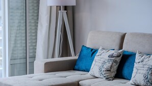 Un salon moderne avec un canapé, une lampe sur pied et une fenêtre avec des rideaux.