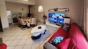 Una sala de estar con televisor, sofá rojo y un comedor con mesa y sillas.