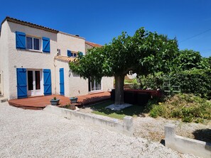 A house with a garden, a pond, and a tree.