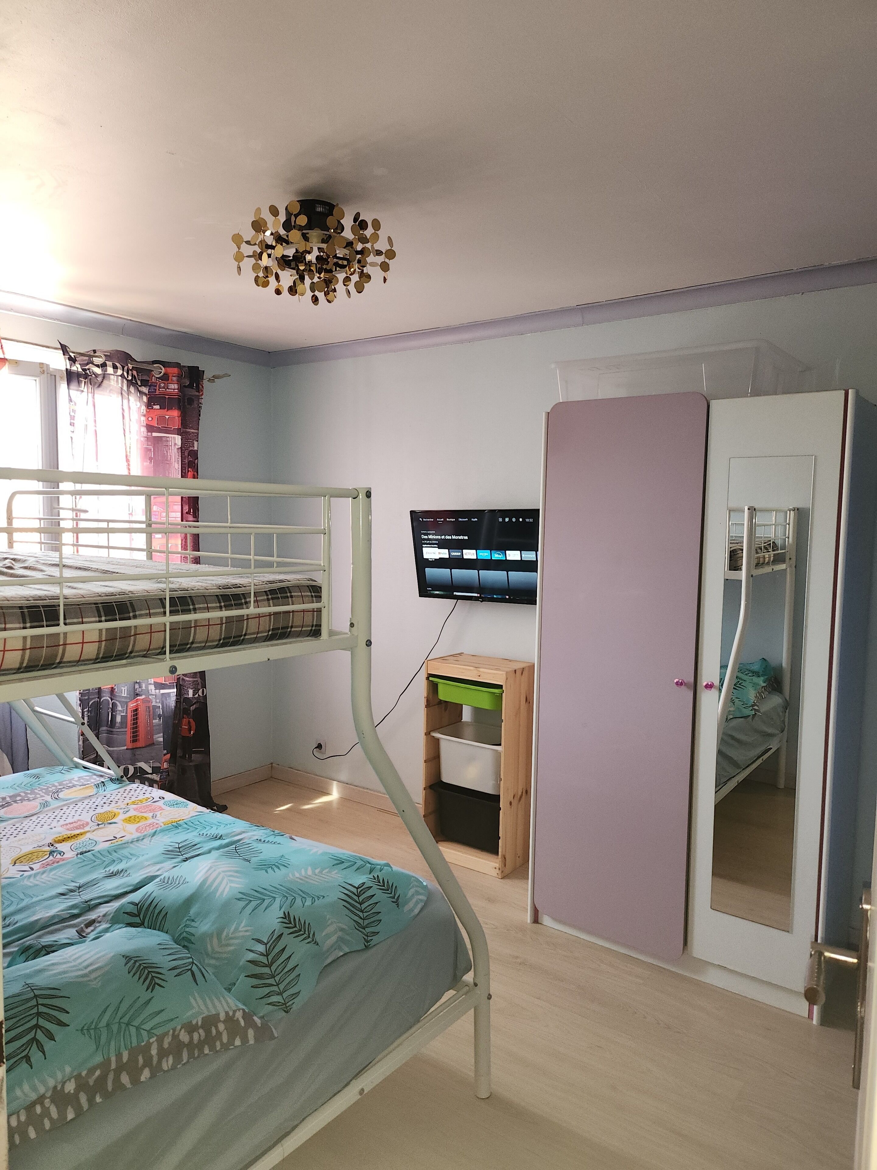 A room with bunk beds, a television, a wardrobe, and a desk with a chair.