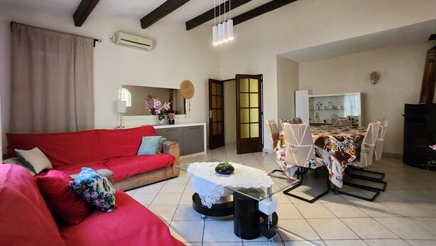 Una sala de estar con un sofá rojo, una mesita de centro y un comedor con sillas y una mesa.
