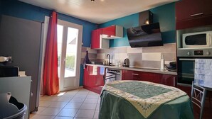 Una cocina compacta con microondas, horno y armarios rojos.