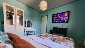 Un dormitorio con cama, cómoda, televisor y una puerta.