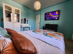 Une chambre à coucher avec un lit, une commode, un téléviseur et une porte.