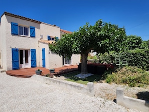 Une maison avec un jardin, un étang et un arbre.