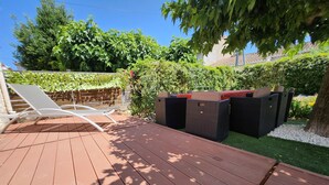 Una terraza de madera con sillones reclinables y mobiliario exterior.