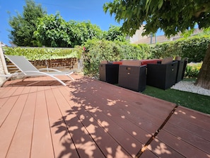 Une terrasse en bois avec des chaises longues et du mobilier d’extérieur.