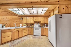 A kitchen with wooden cabinets, a white refrigerator, a stove, and a skylight. - Lakeside Brimwater (Island Park)
