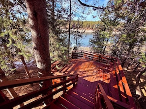 A wooden deck with benches overlooking a forested area and a body of water.