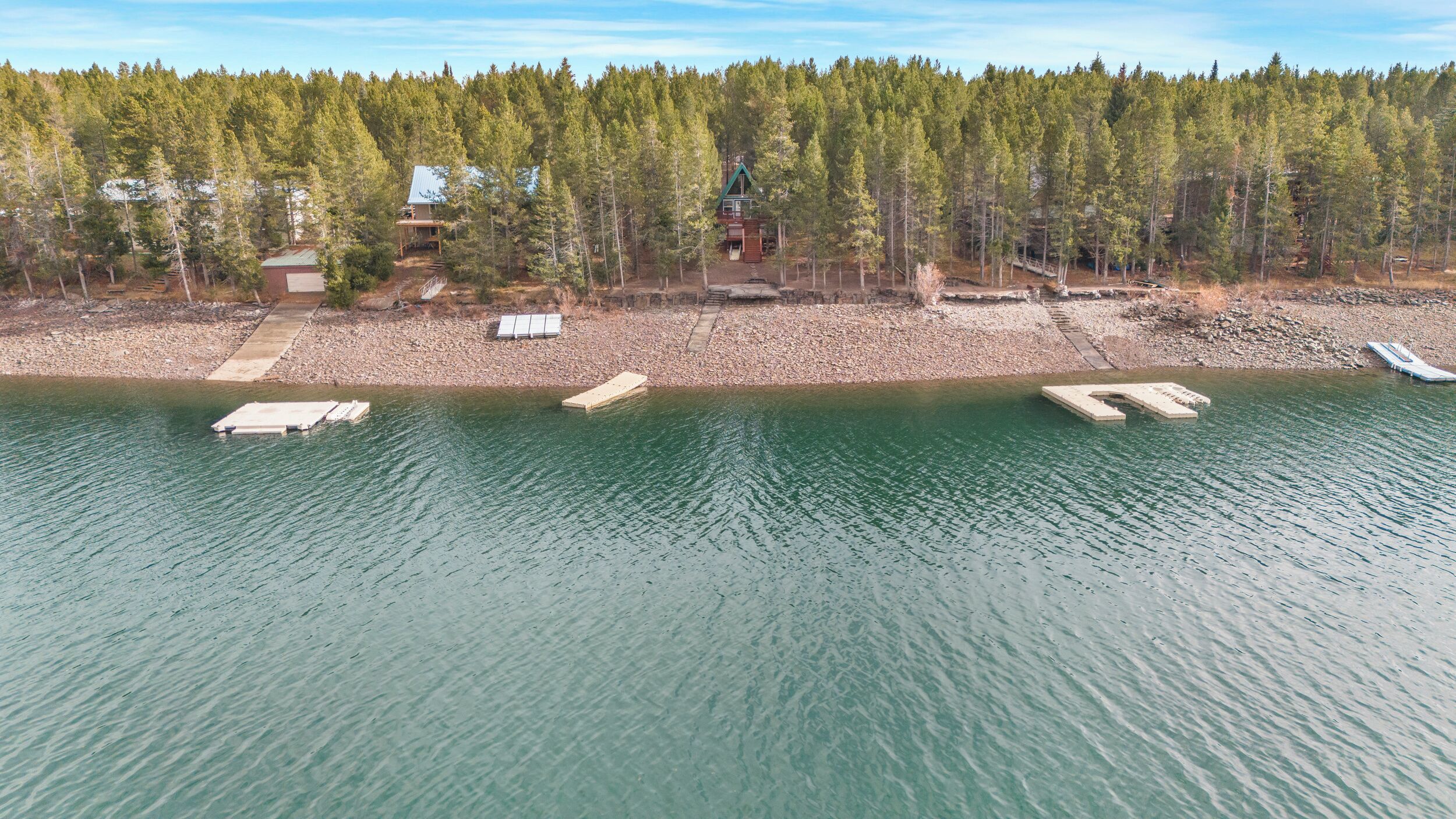 A lakeside cabin with a dock, surrounded by dense forest.