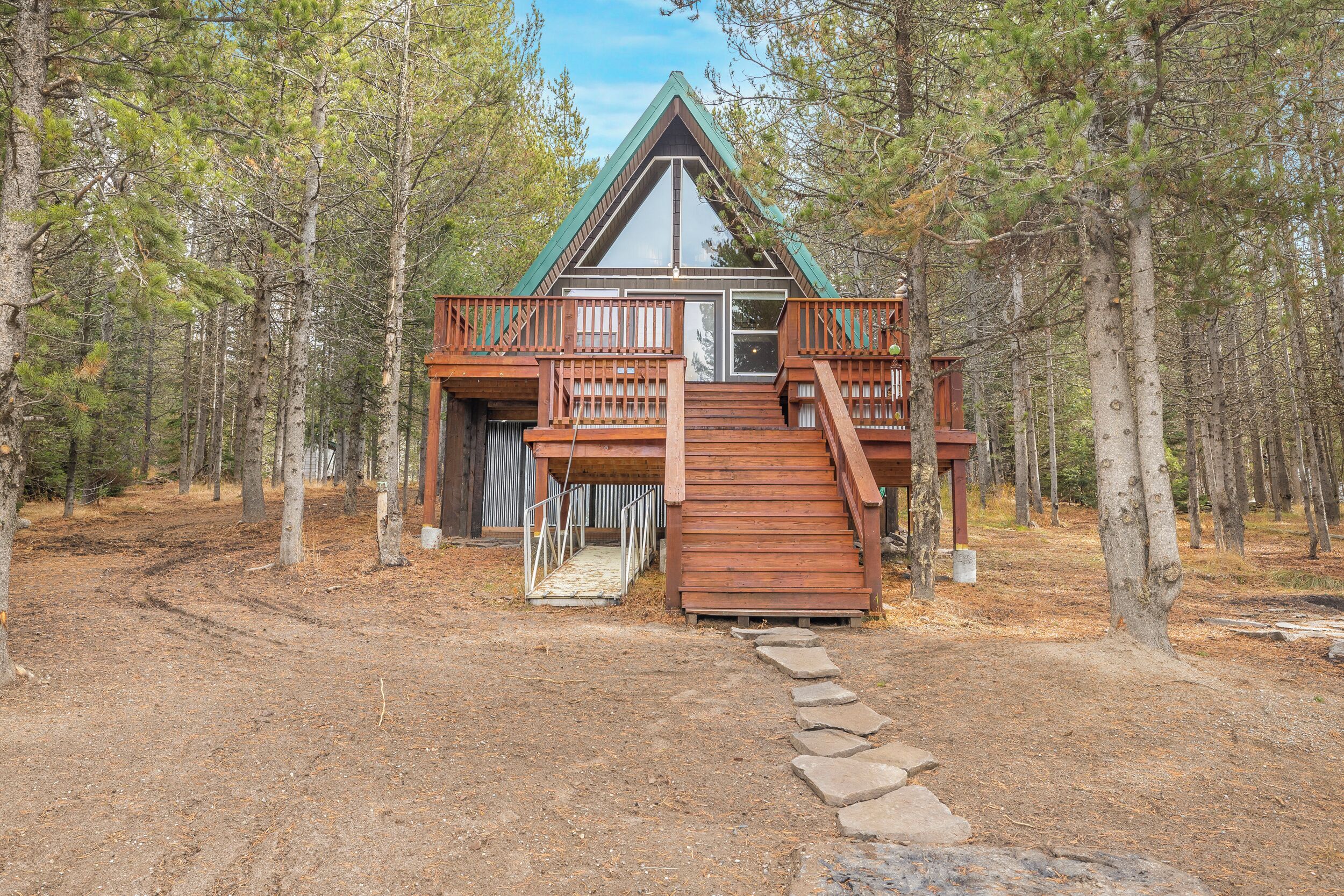 Une cabane dotée d’une terrasse en bois, d’un escalier et d’une rambarde en métal.