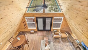 L’intérieur d’un chalet en bois comprend un coin repas, un canapé et un ventilateur de plafond.