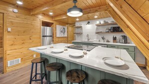Une cuisine avec des murs en bois, un grand îlot central avec des tabourets, un réfrigérateur et un four à micro-ondes.
