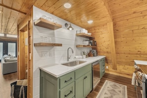 A kitchen with wooden walls, white countertops, and green cabinets. - Lakeside Dockside (Island Park)