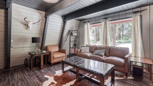 A cozy living room with a leather sofa, a marble coffee table, and a cowhide rug. - Shotgun Chalet (Island Park)
