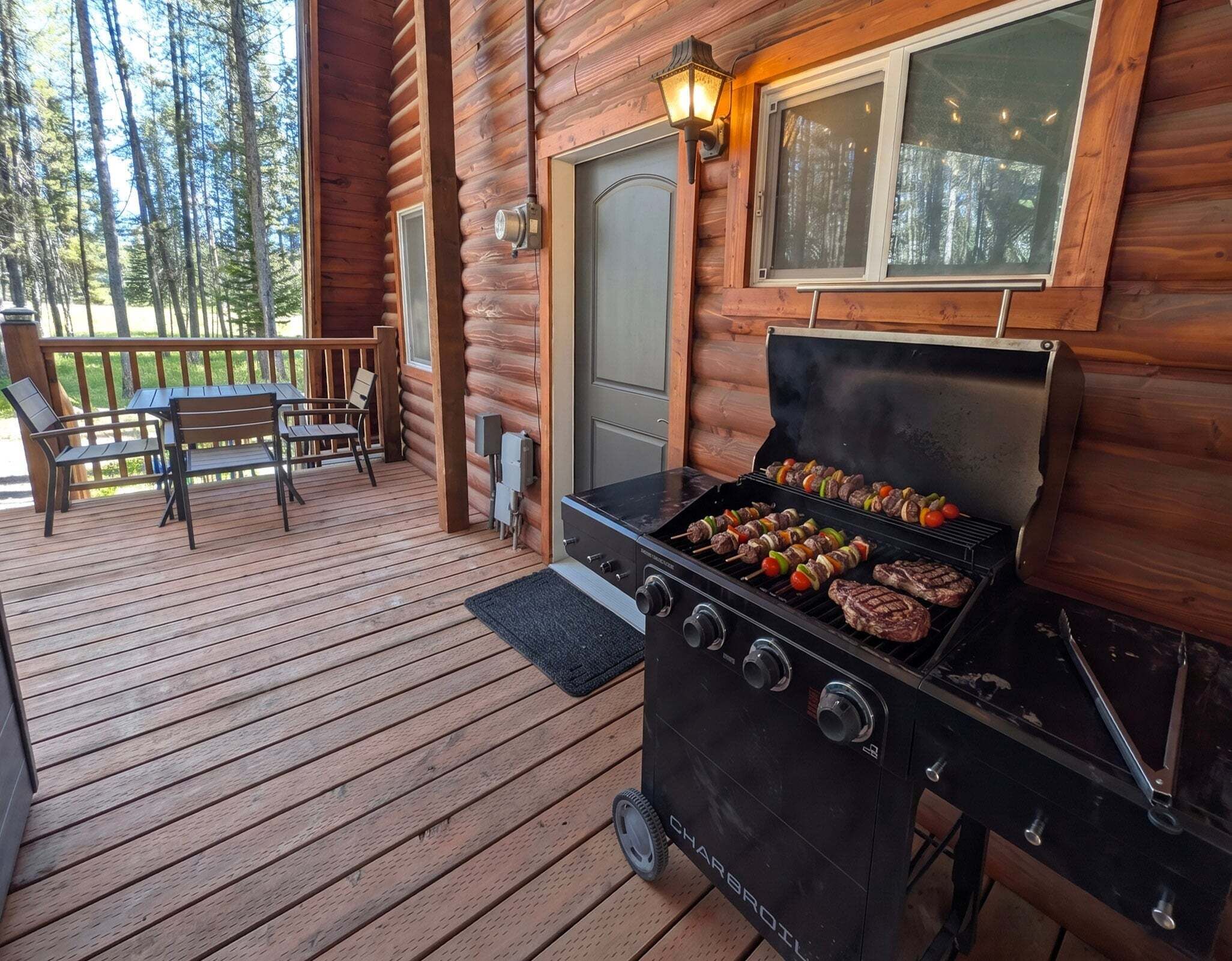 Una terraza de madera con una parrilla, sillas y una puerta.