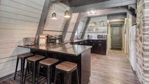 Eine moderne Küche mit Bar, Holzboden und einer Wand aus Stein.